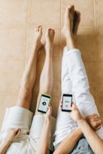 Person in White Pants Sitting on Brown Ceramic Floor Tiles